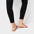 Person wearing black leggings and pink sandals on a white background