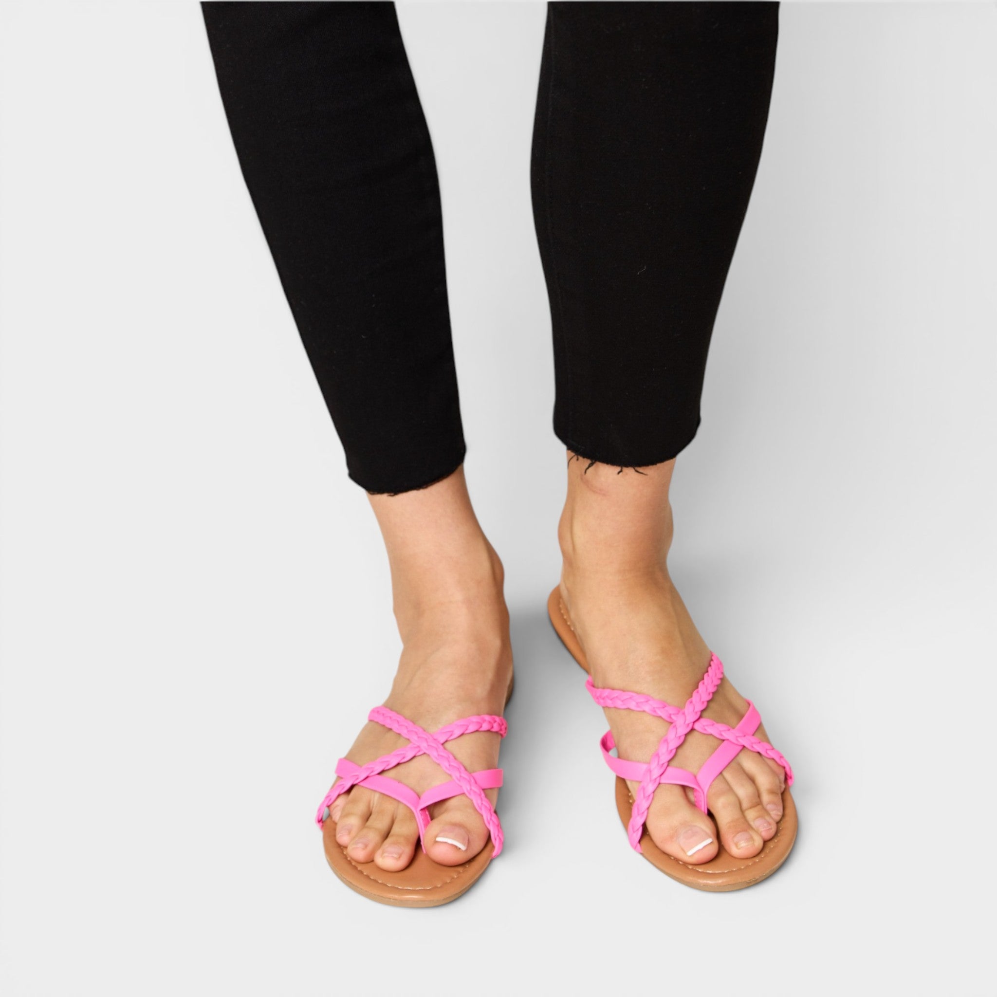 Person wearing pink strappy sandals on a plain background