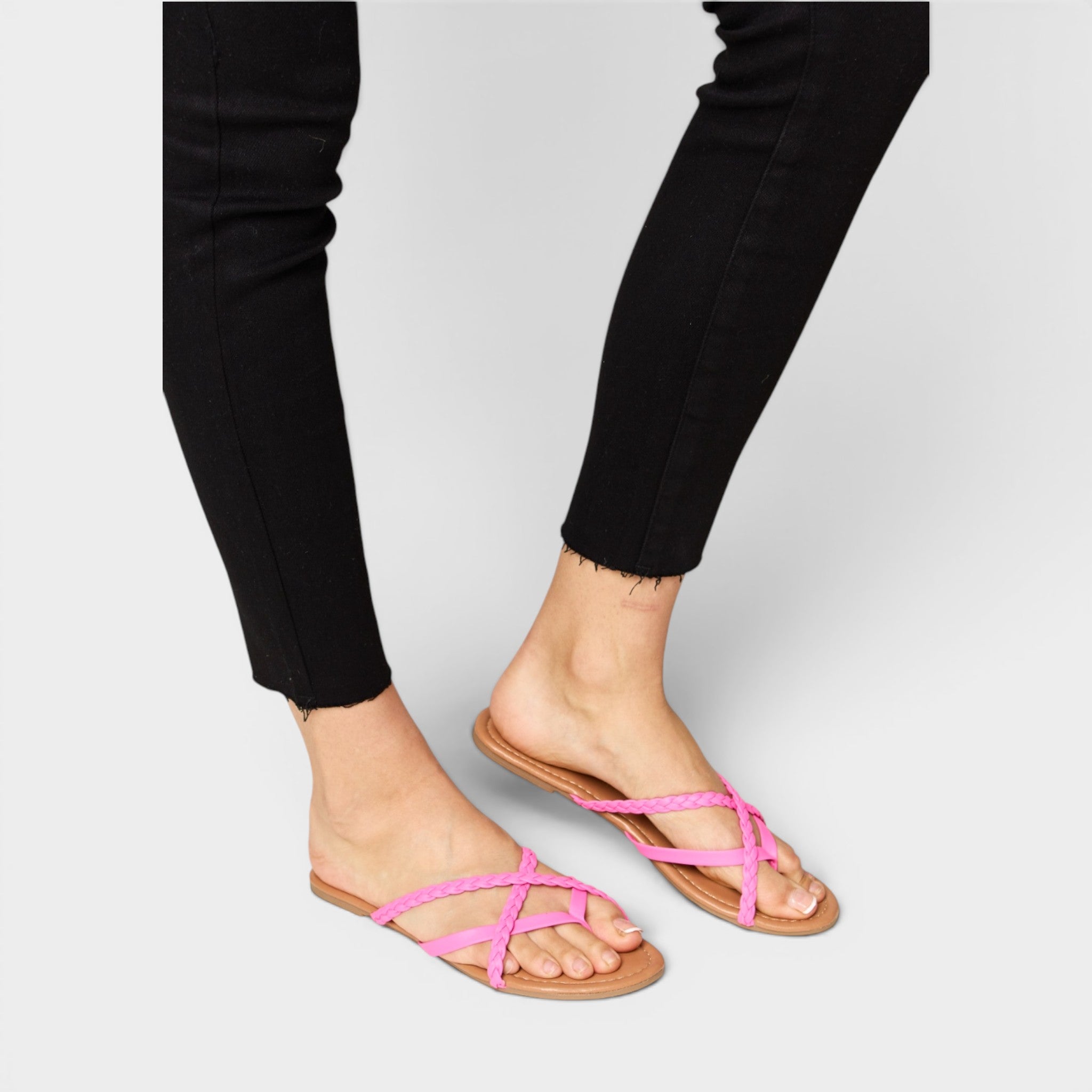 Person wearing black pants and pink sandals on a light gray background