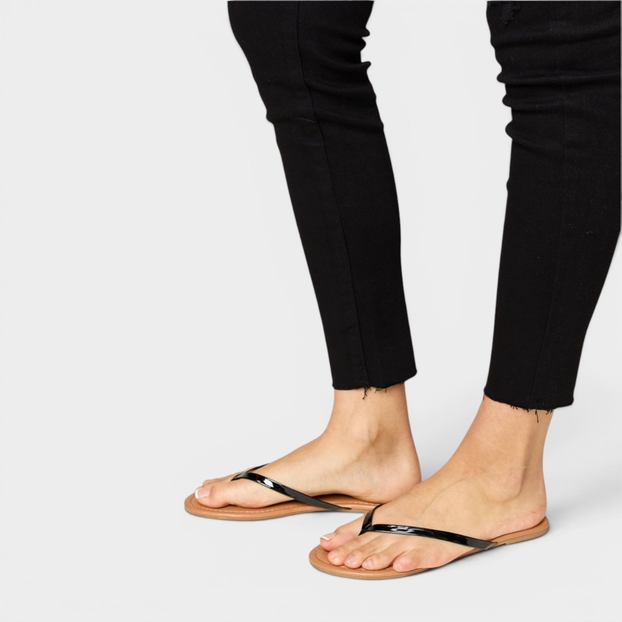 Person wearing black flip-flops on a plain background