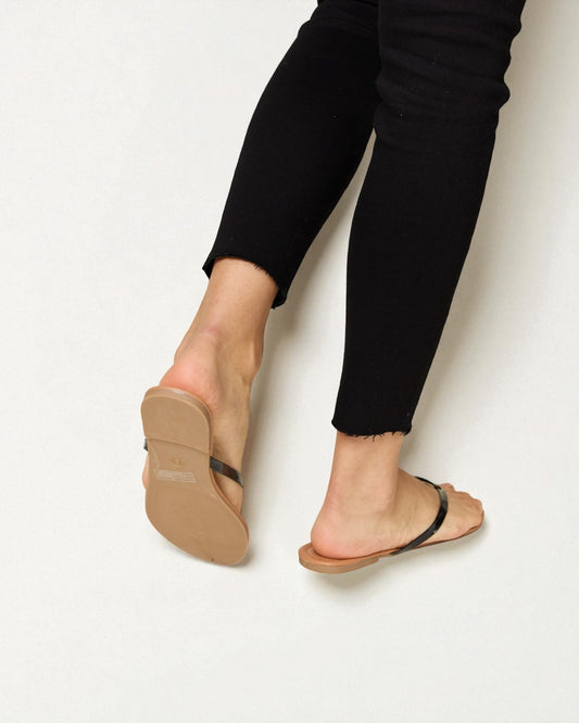 Person wearing black pants and tan sandals on a white background