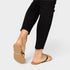 Person wearing black pants and tan sandals on a white background