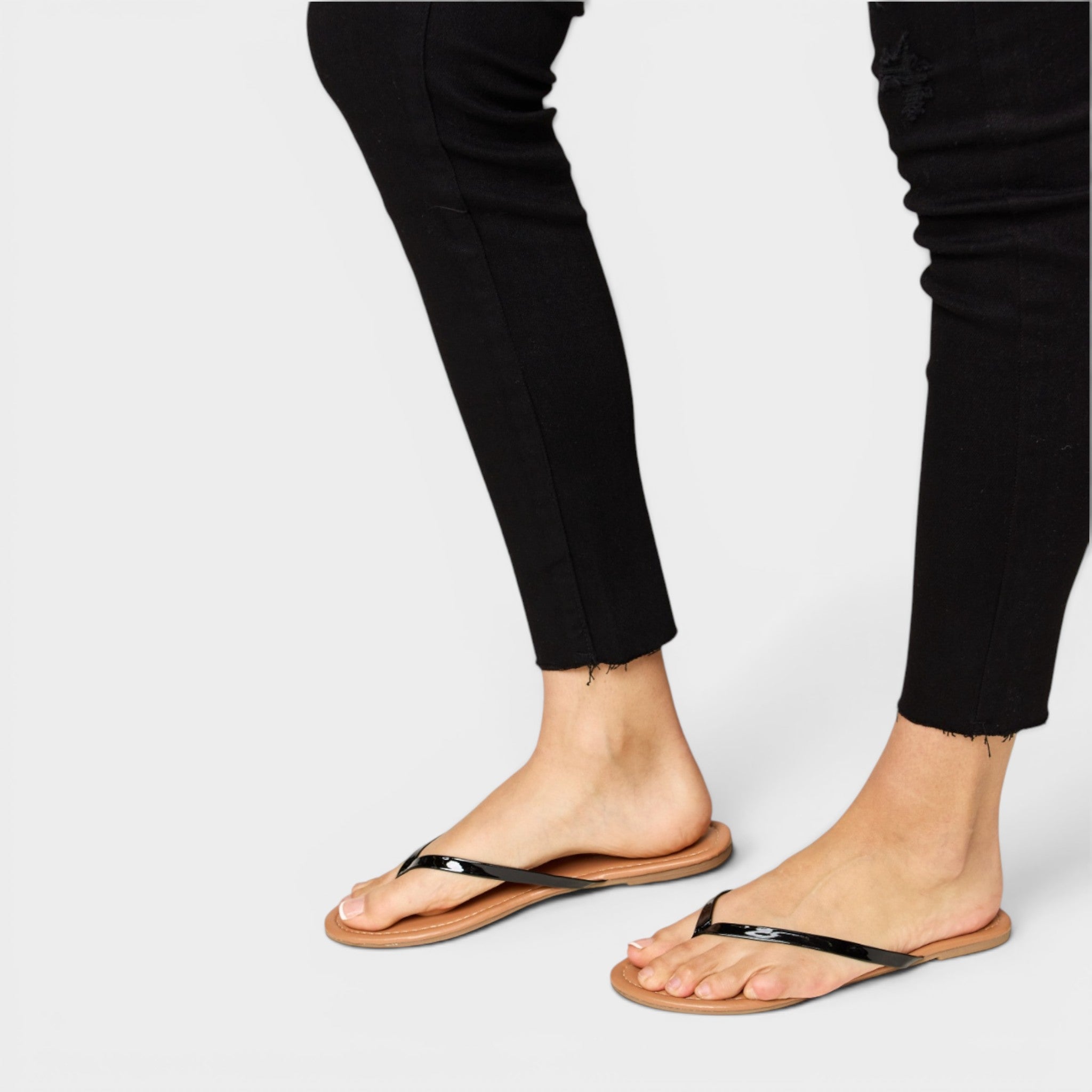 Person wearing black flip-flops on a plain background