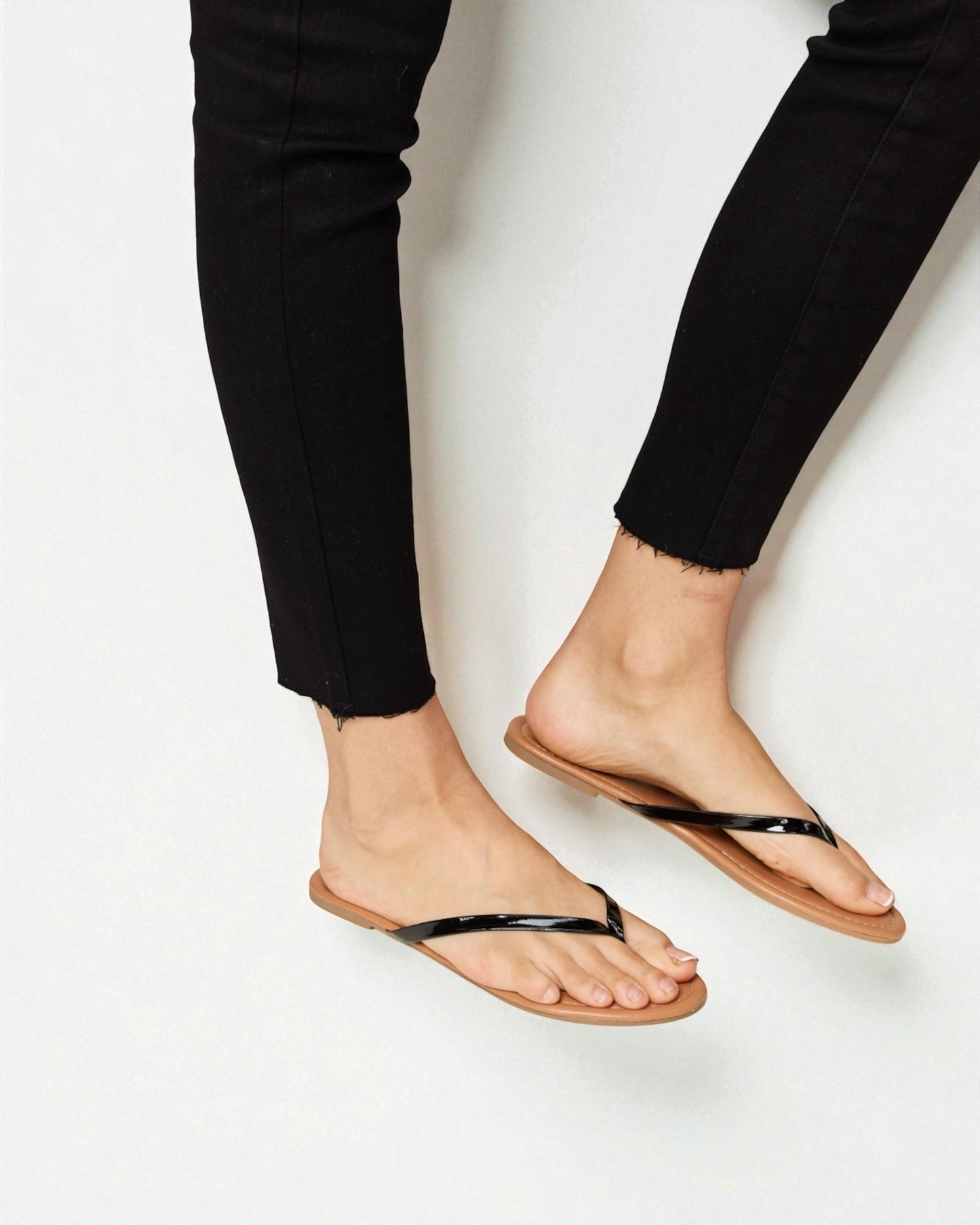 Person wearing black flip-flops on a white background