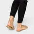 Gold open-toe shoes worn with black pants on a light gray background
