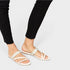 White sandals worn with black pants on a light gray background
