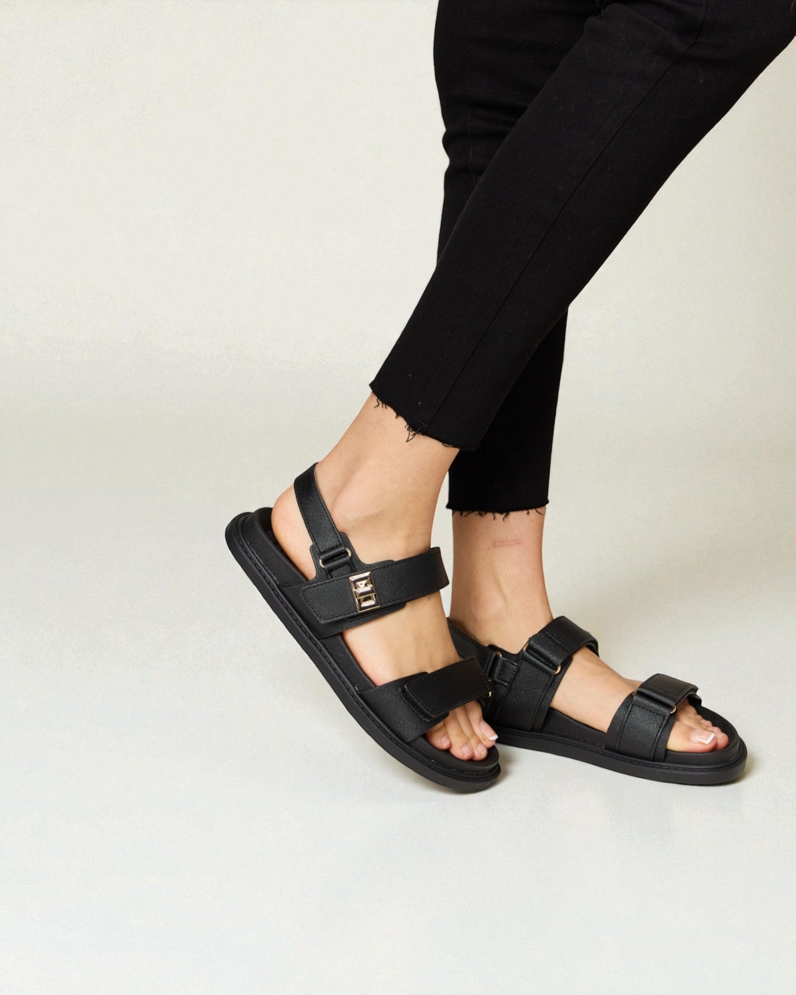 Person wearing black sandals on a plain background