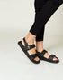 Person wearing black sandals on a plain background