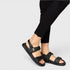 Black sandals worn with black pants on a light gray background
