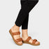 Brown woven sandals worn with black pants on a light gray background