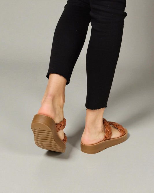 Brown sandals worn with black pants on a neutral background