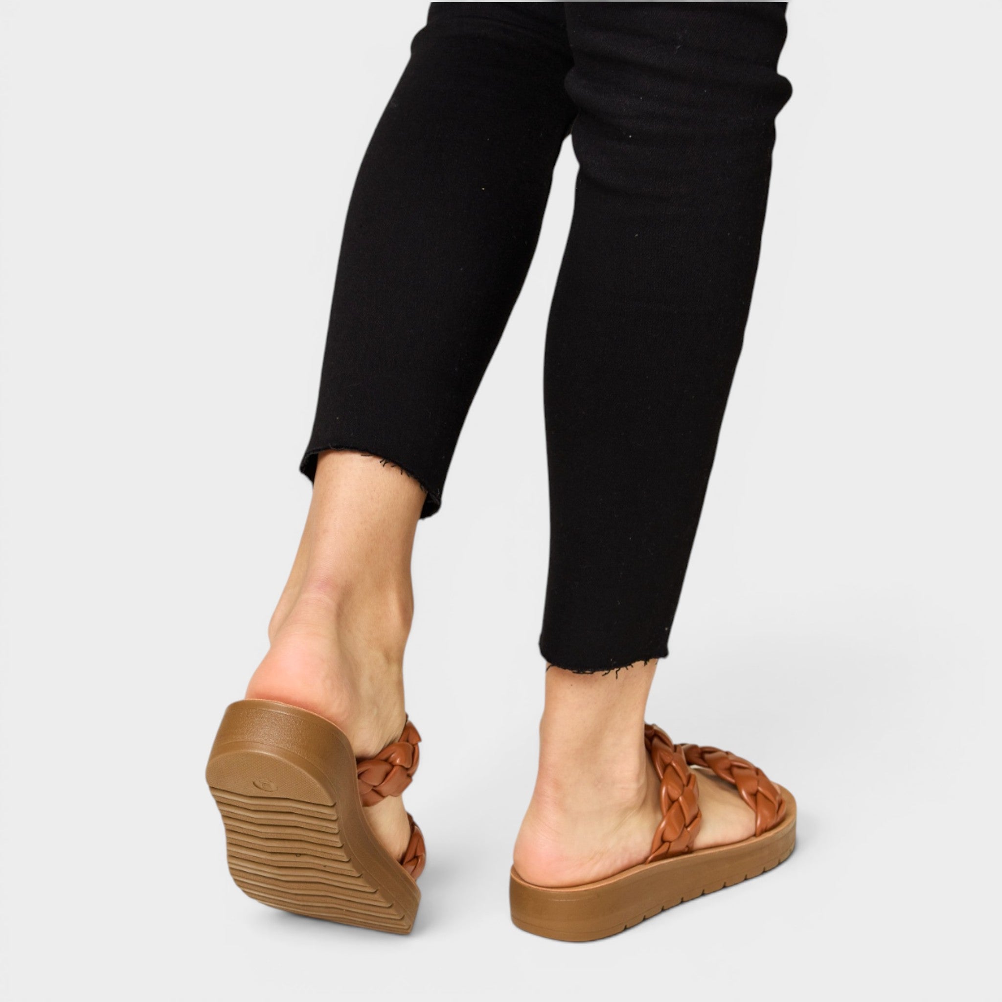 Brown sandals worn with black pants on a light gray background