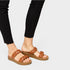 Brown woven sandals worn with black pants on a light gray background