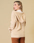 Woman wearing a beige hoodie against a beige background