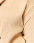 Close-up of a cream or light beige knit fabric, showing the detailed texture of the knit pattern and soft folds.