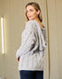 Woman wearing a cable knit sweater in a neutral setting