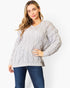 A woman modeling a light gray cable-knit sweater with balloon sleeves, paired with dark blue jeans, against a plain white studio background.