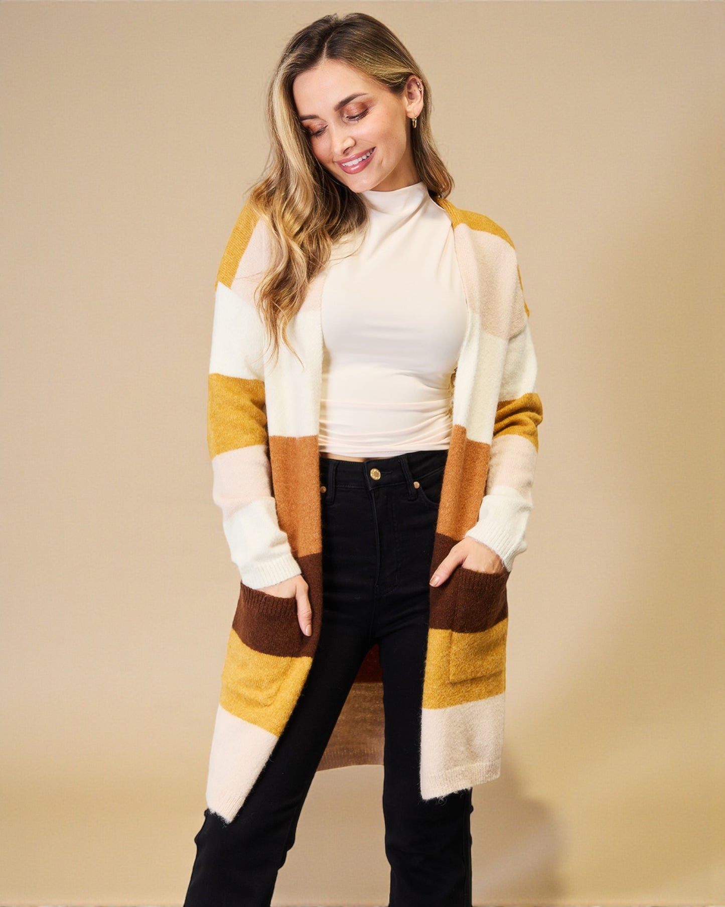 Woman wearing a striped cardigan over a white turtleneck on a beige background
