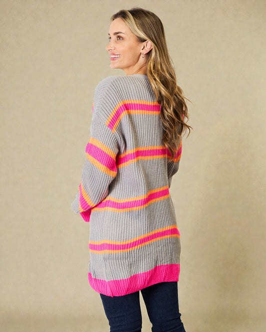 Woman wearing a gray sweater with pink and orange stripes against a beige background