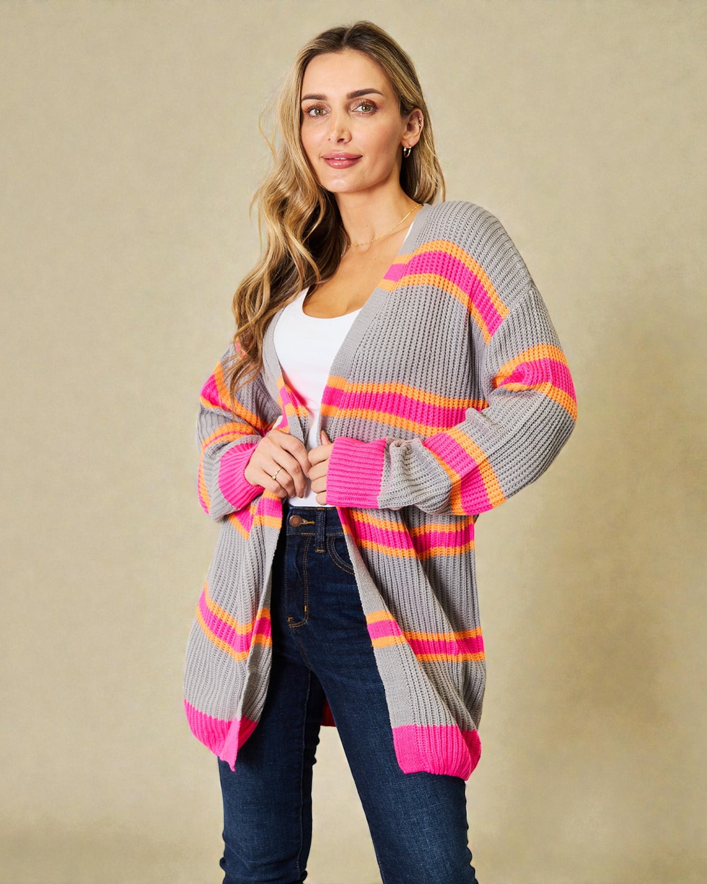 Woman wearing a gray cardigan with pink and orange stripes on a beige background