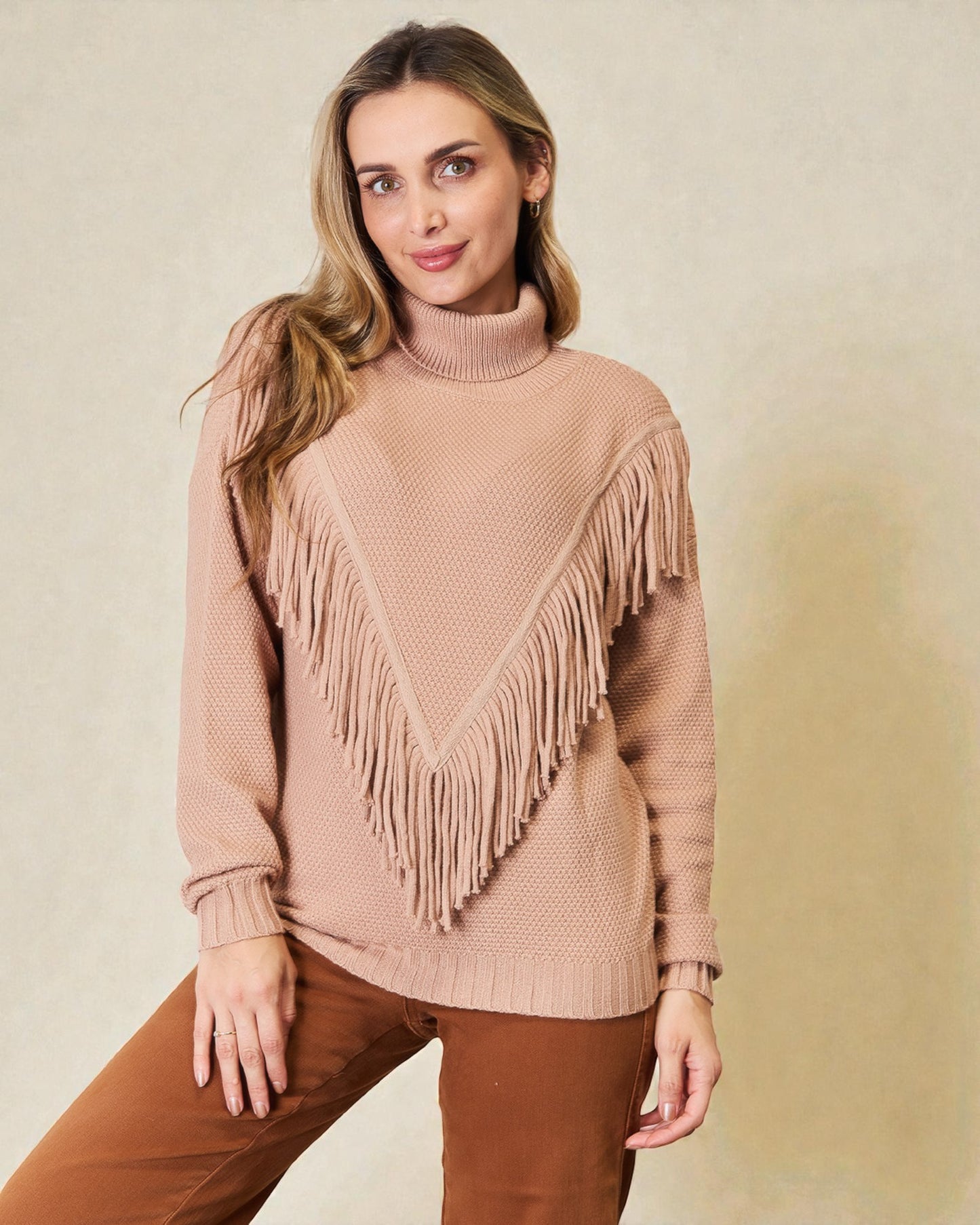 Woman wearing a beige sweater with fringe details on a beige background