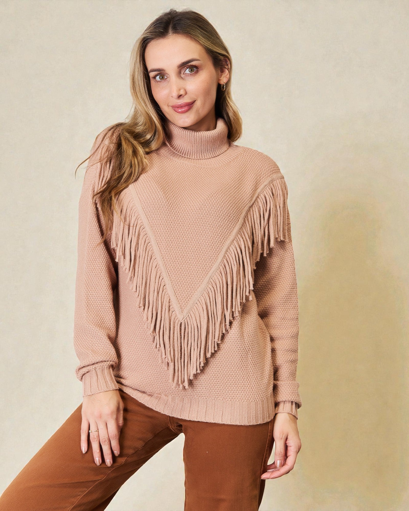 Woman wearing a beige sweater with fringe details on a beige background