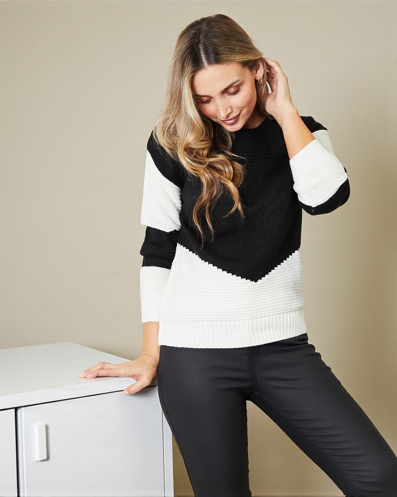 Woman wearing a black and white sweater against a beige background