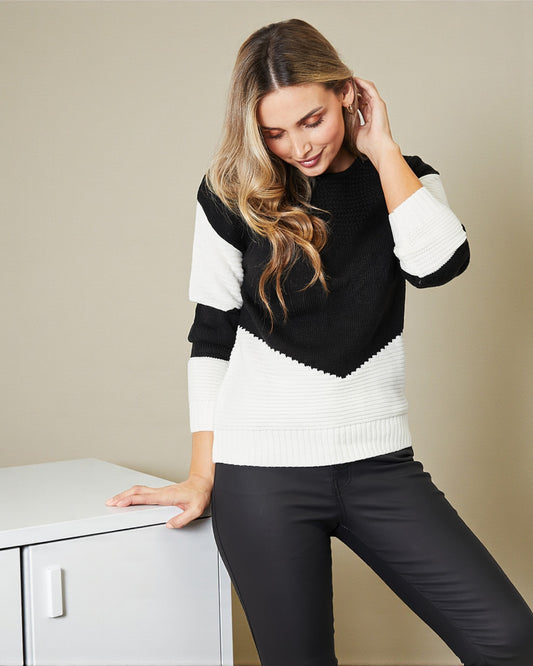 Woman wearing a black and white sweater against a beige background
