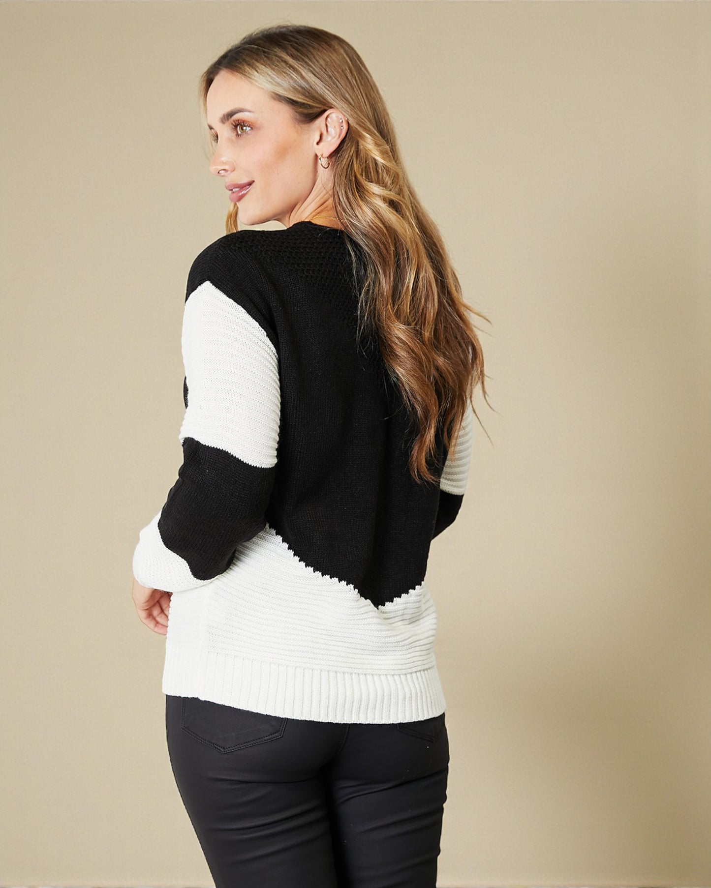 Woman wearing a black and white sweater against a beige background