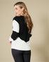 Woman wearing a black and white sweater against a beige background