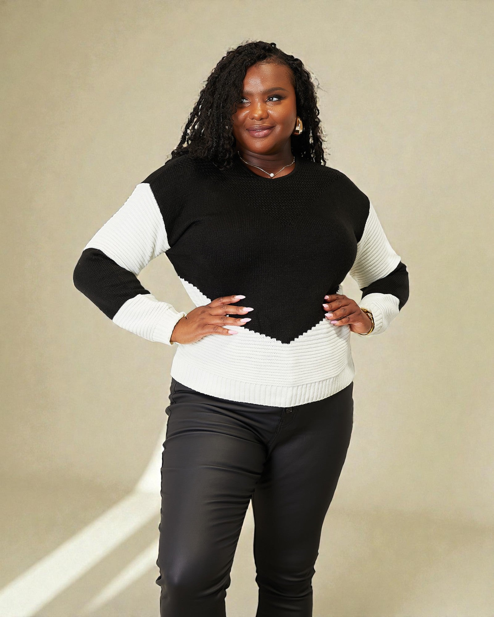 Woman wearing a black and white sweater against a beige background