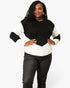 A woman modeling a color-block knit sweater with a black yoke and black ribbed sleeves, paired with black pants, against a plain white studio background.