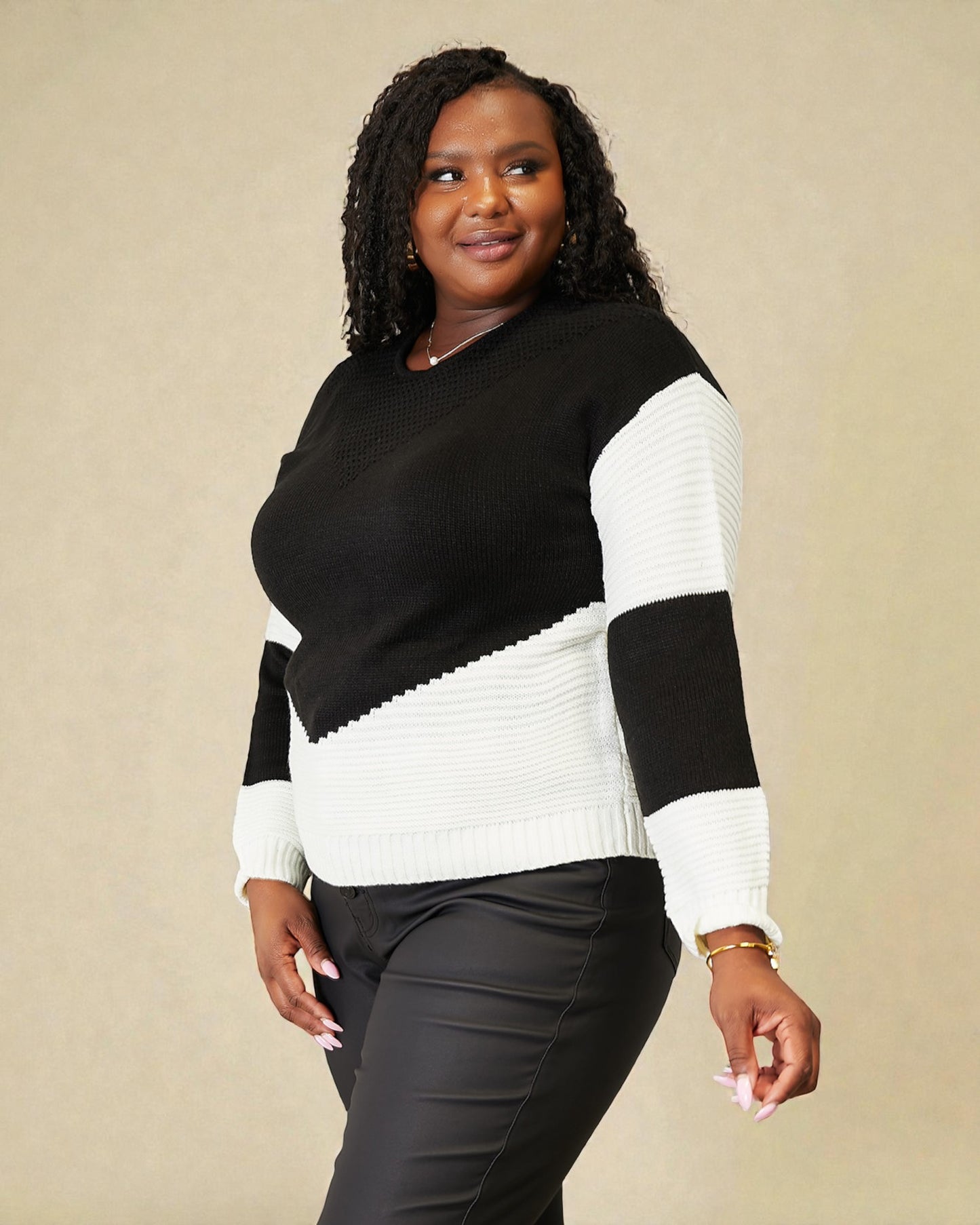 Woman wearing a black and white sweater against a beige background