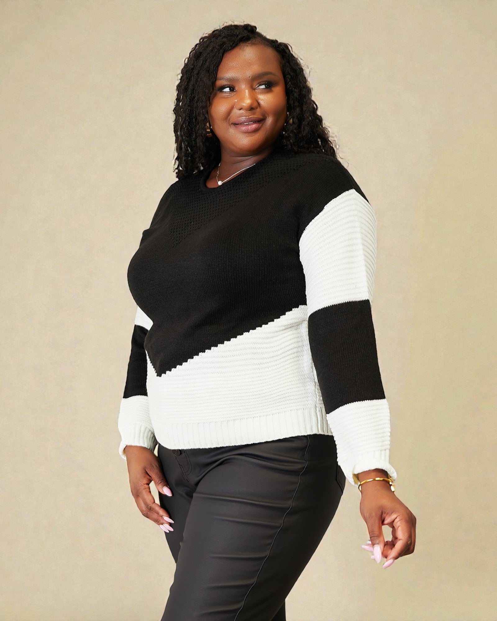 Woman wearing a black and white sweater against a beige background