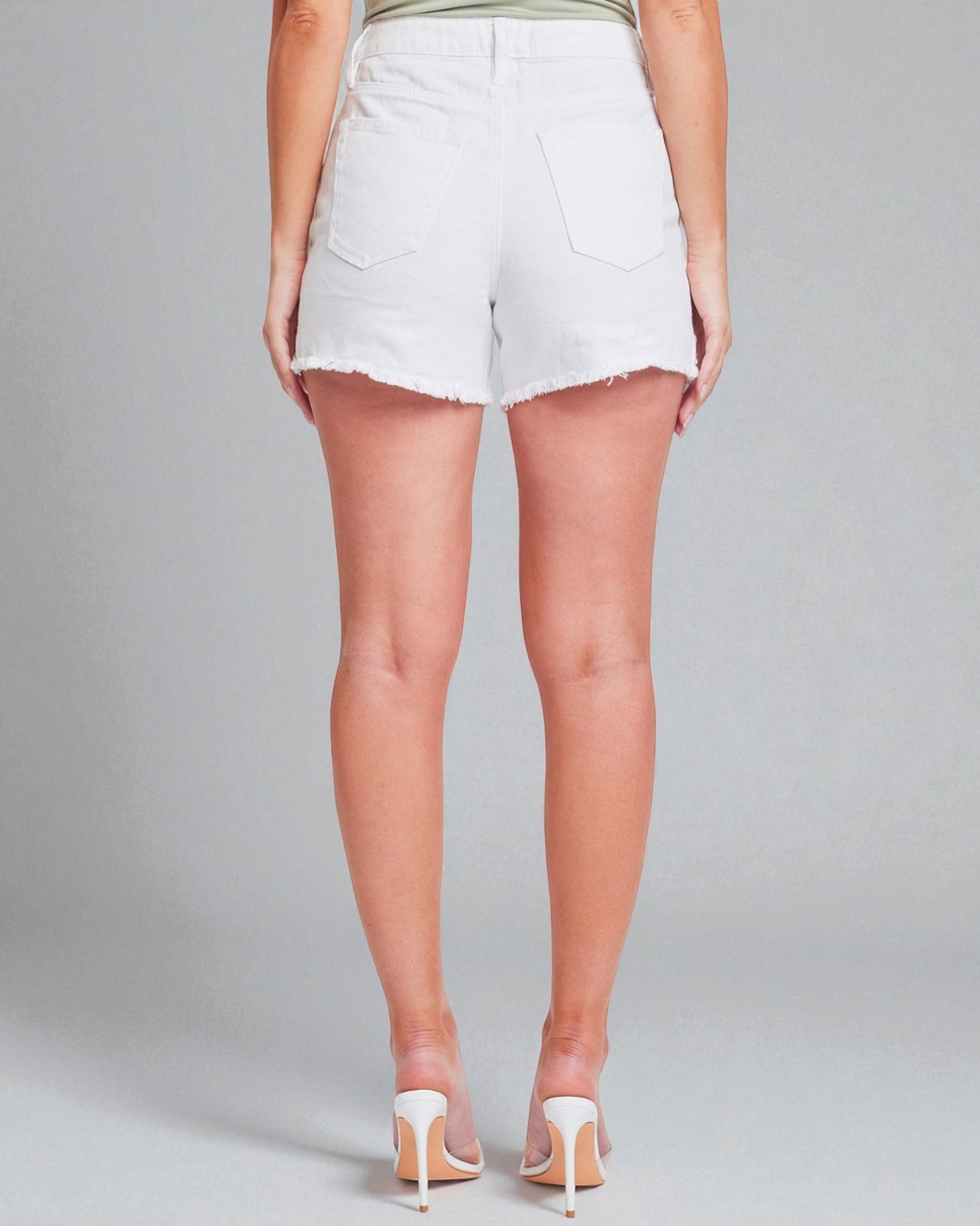 Person wearing white denim shorts on a plain background