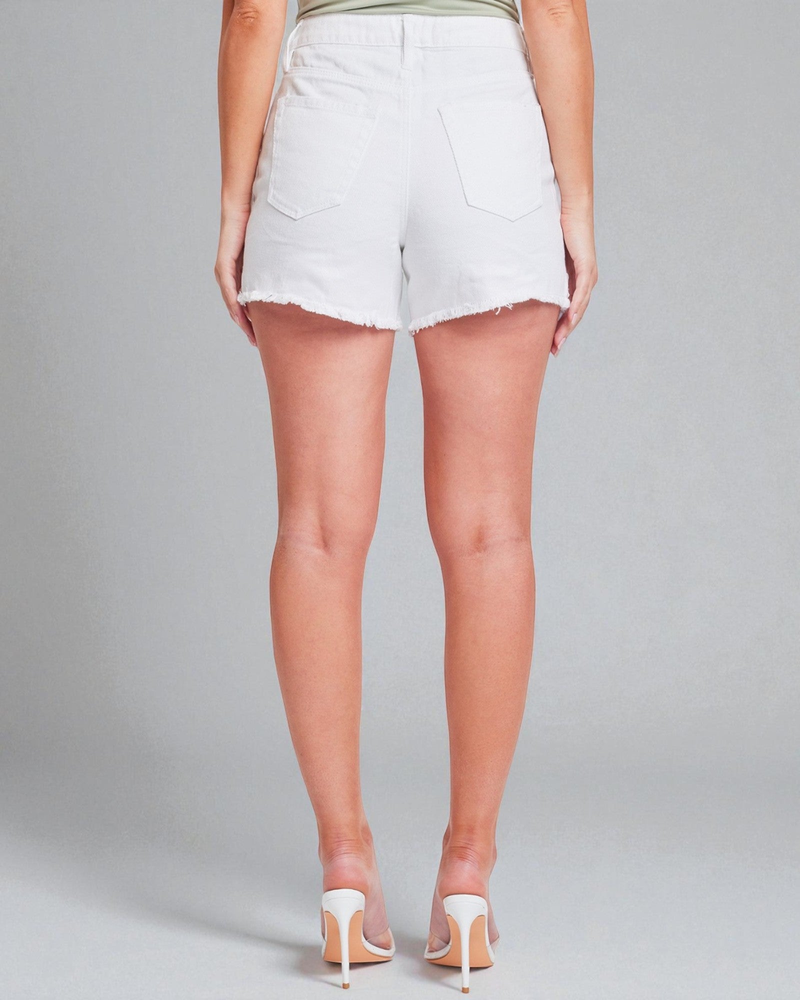 Person wearing white denim shorts on a plain background