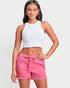 Woman wearing a white crop top and pink shorts on a light gray background