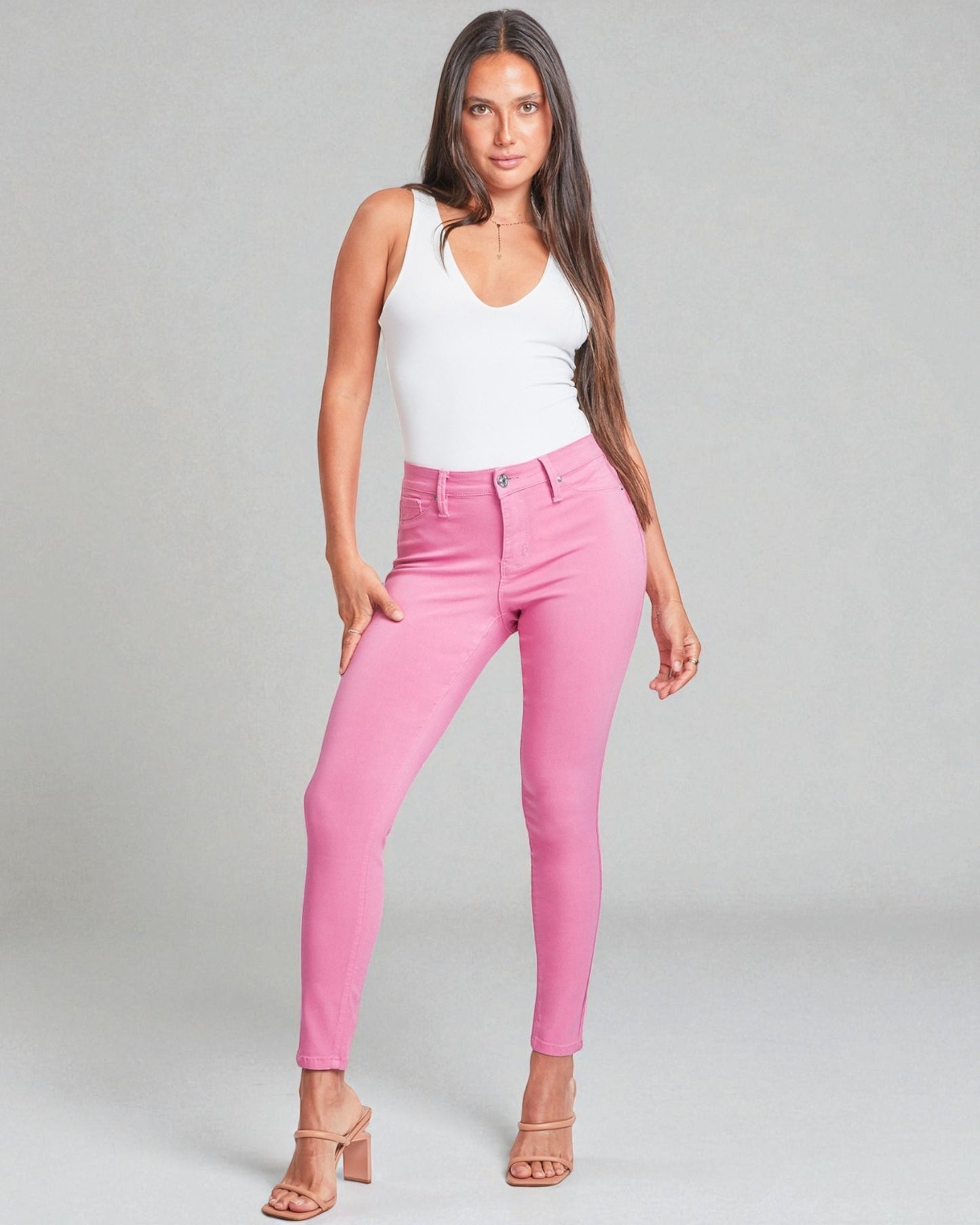 Woman wearing pink pants and a white top on a gray background