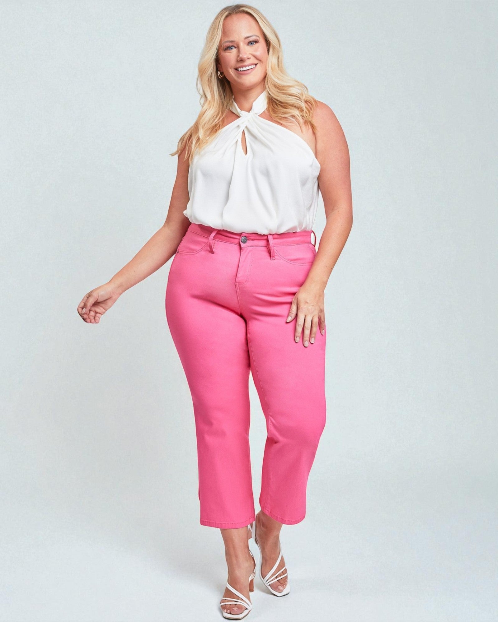 Woman wearing a white top and pink pants on a light gray background