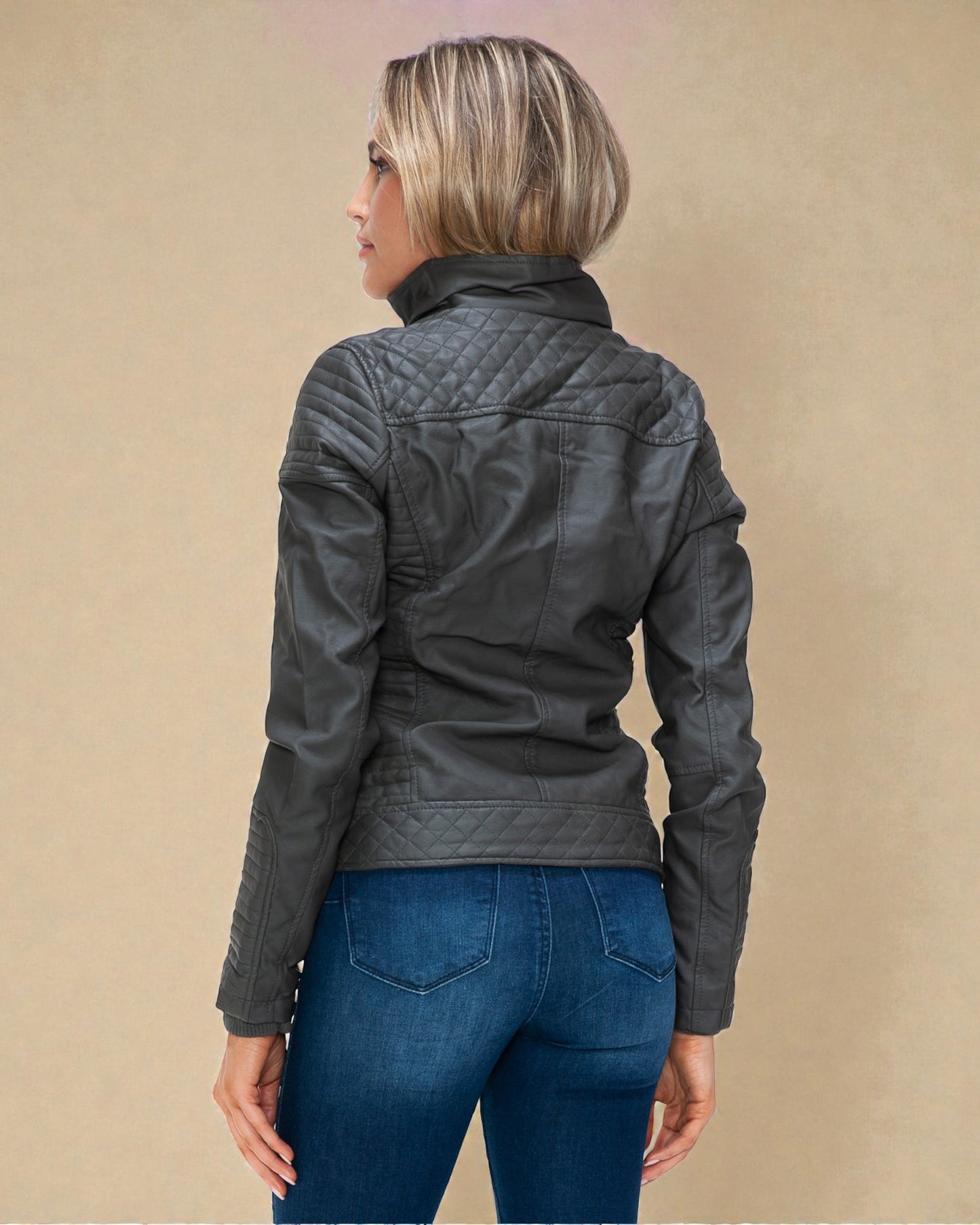 Person wearing a dark quilted jacket and blue jeans on a beige background