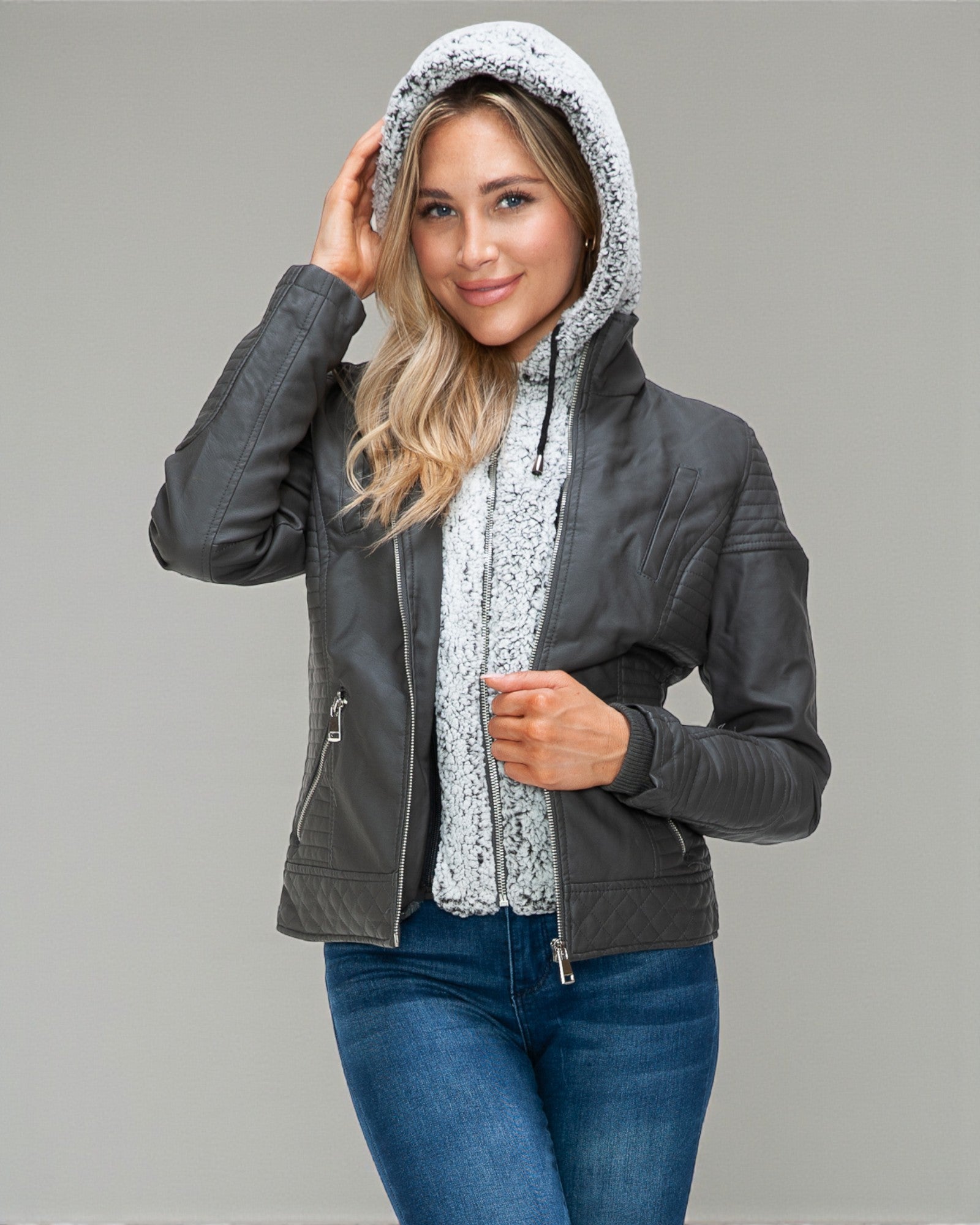 Woman wearing a gray jacket with a hood on a gray background