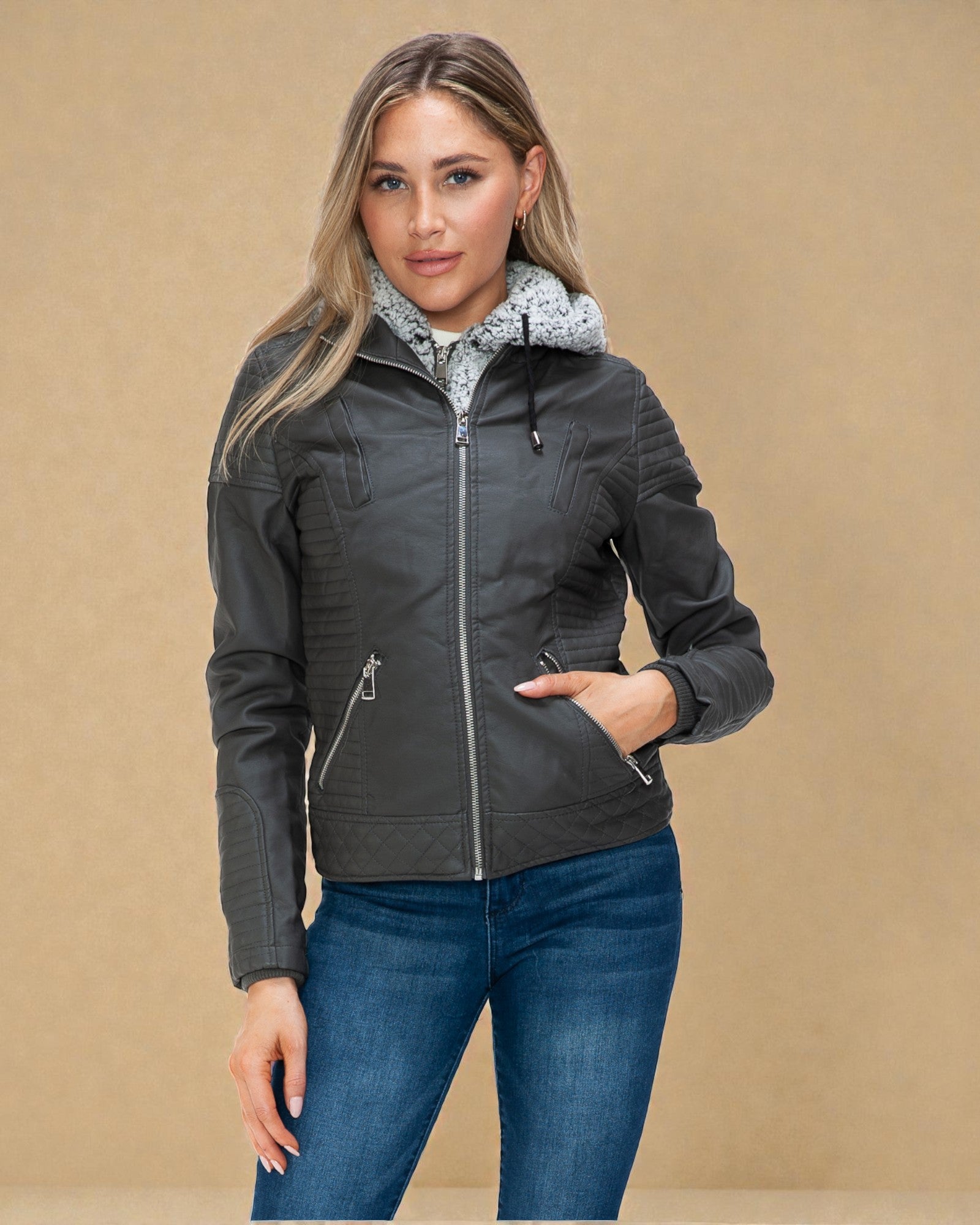 Woman wearing a dark gray jacket with a patterned hood against a beige background