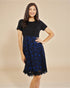 Woman wearing a black top and blue lace skirt on a beige background
