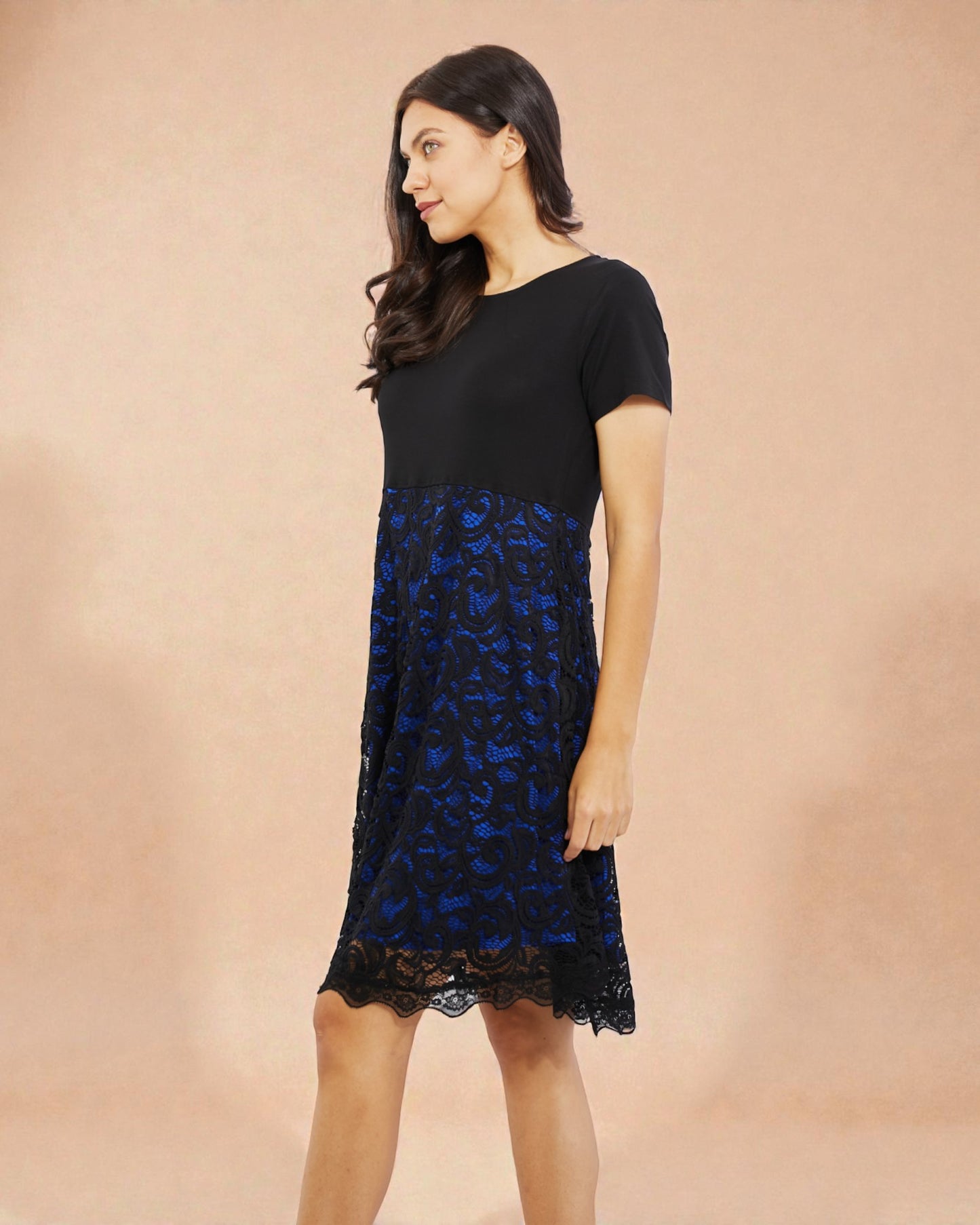 Woman wearing a black dress with blue floral pattern on a beige background
