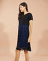 Woman wearing a black dress with blue floral pattern on a beige background