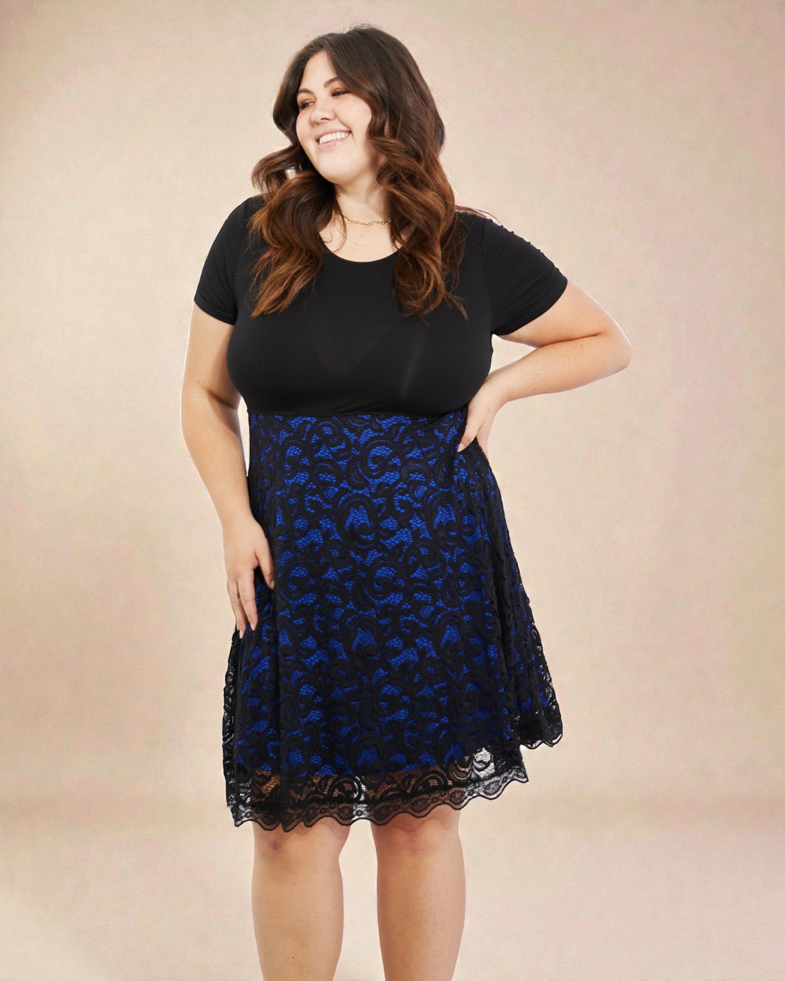 Woman wearing a black top and blue lace skirt on a beige background