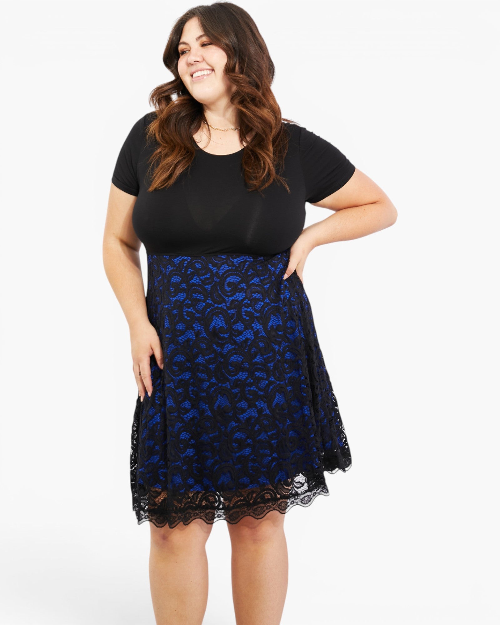 A woman modeling a black short-sleeve top and a blue and black floral lace skater skirt against a plain white studio background.
