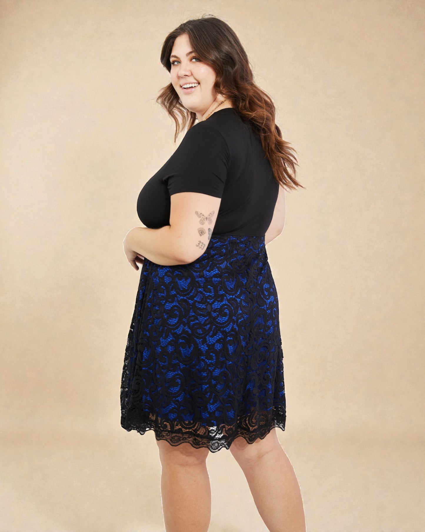 Woman wearing a black lace dress with a blue pattern on a beige background