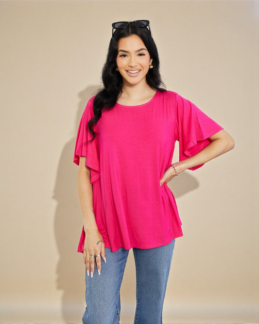 Woman wearing a bright pink blouse with ruffled sleeves against a beige background