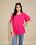 Woman wearing a bright pink blouse with ruffled sleeves against a beige background